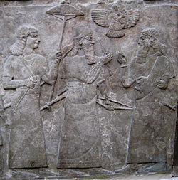 14r - Ashurnasirapal II with official after a battle, alien patron god Ashur in his sky-disc above
